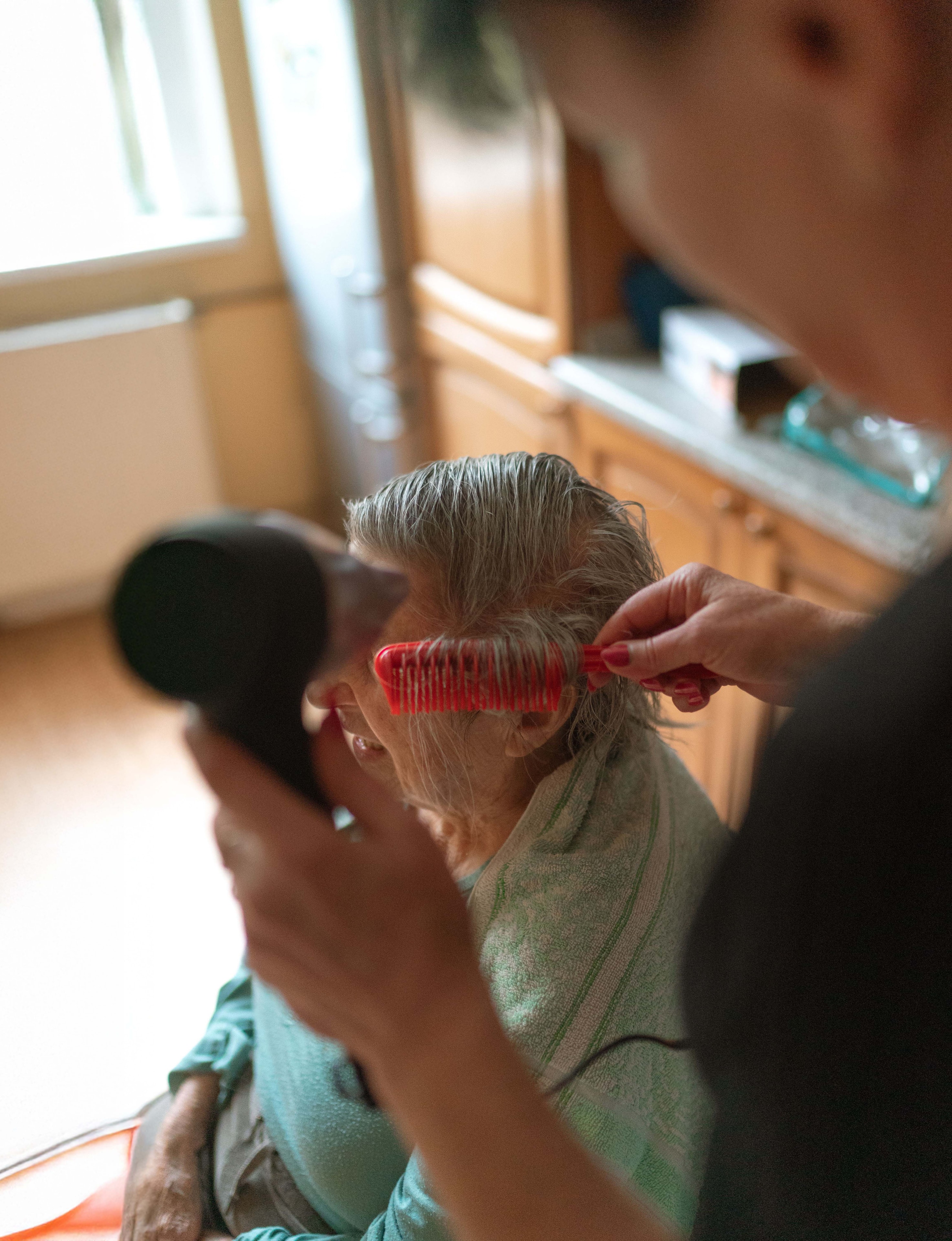 Caregiver gently combing a client's hair — personal care delivered with dignity