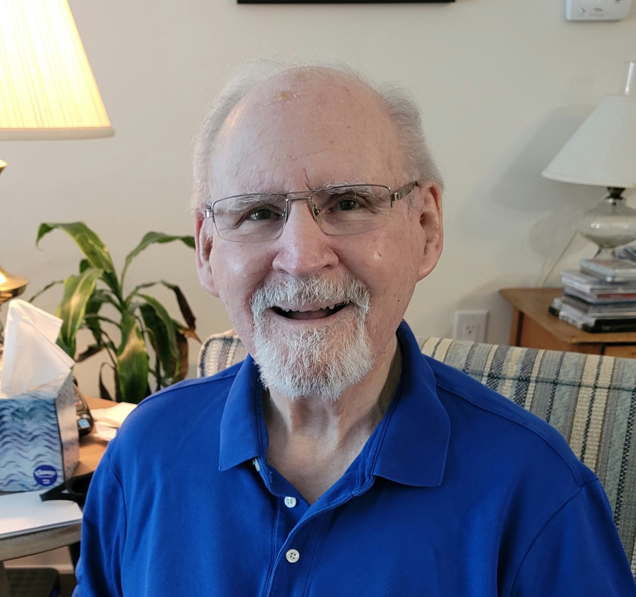 Senior man smiling in blue shirt indoors, years of care and connection — Peaceful Place Home Care, Matthews NC